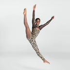 A young dancer in a dynamic leap, wearing a leopard-print leotard and sheer black mesh sleeves, captured against a seamless light gray studio background.