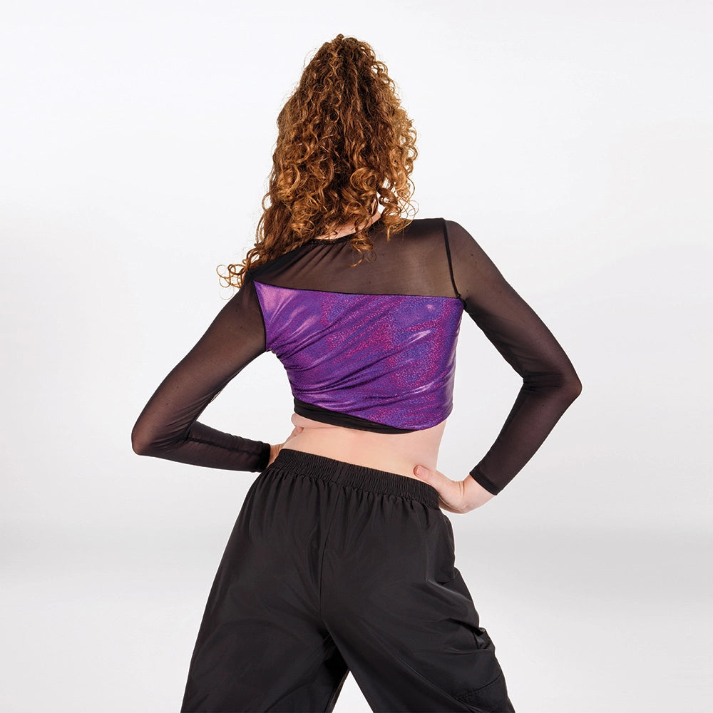 A model viewed from behind wearing a black mesh long-sleeve crop top with a purple metallic glittery back panel, paired with black pants, against a light gray studio background.