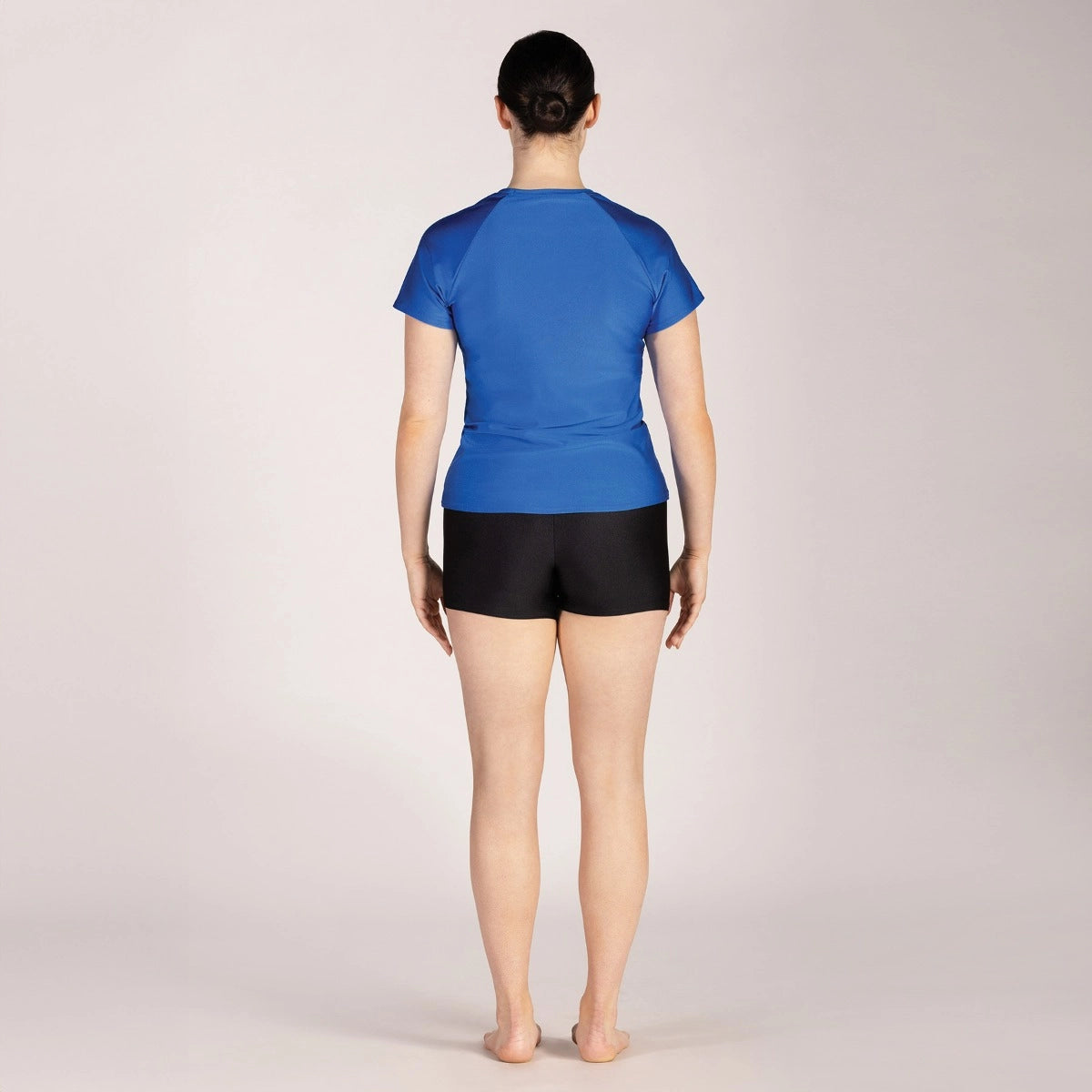 Person wearing a blue top and black shorts on a plain background