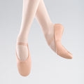 Ballet shoes worn with tights on a light gray background