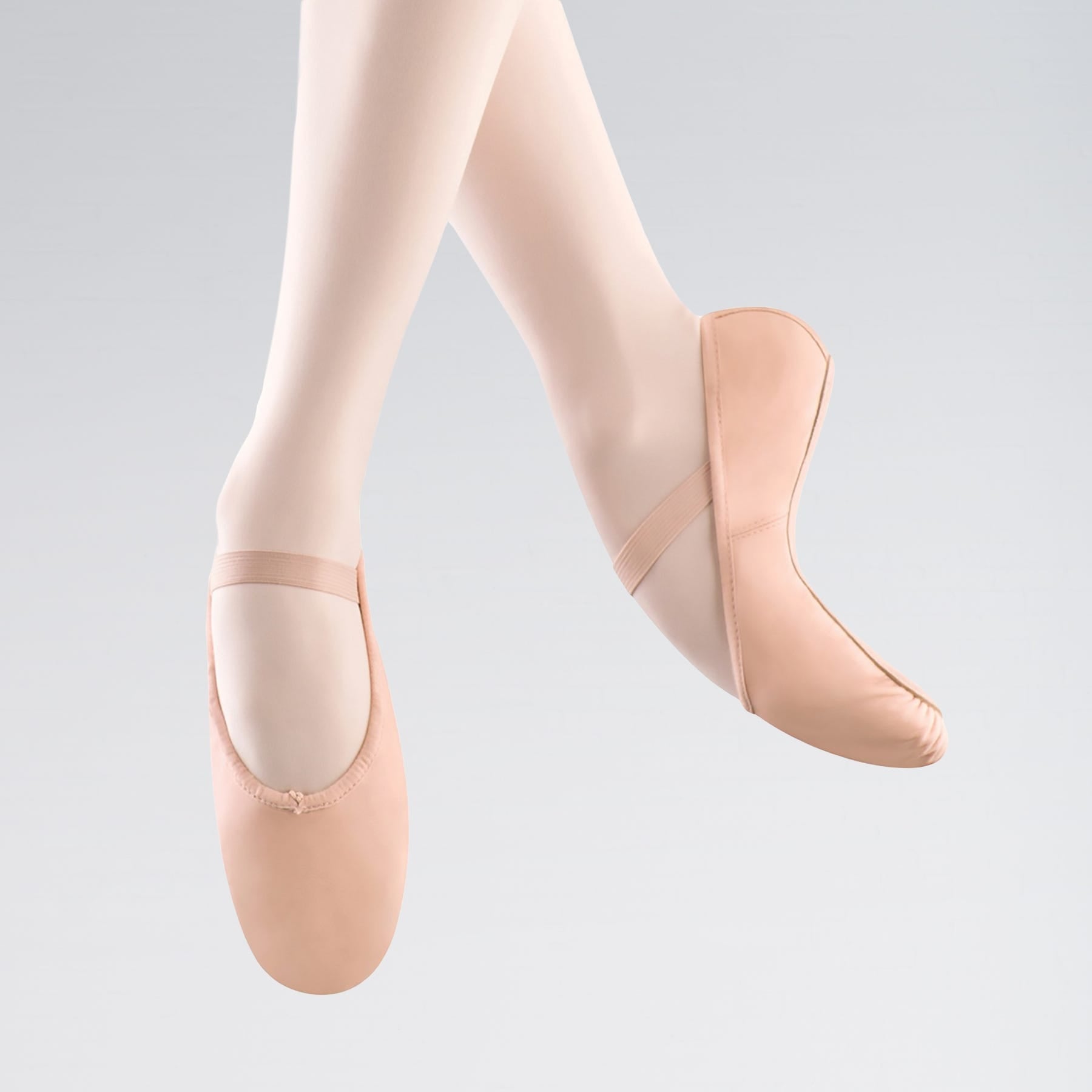 Ballet shoes worn with tights on a light gray background