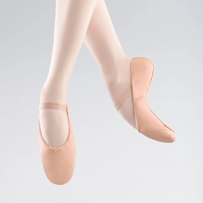 Ballet shoes worn with beige tights on a light gray background