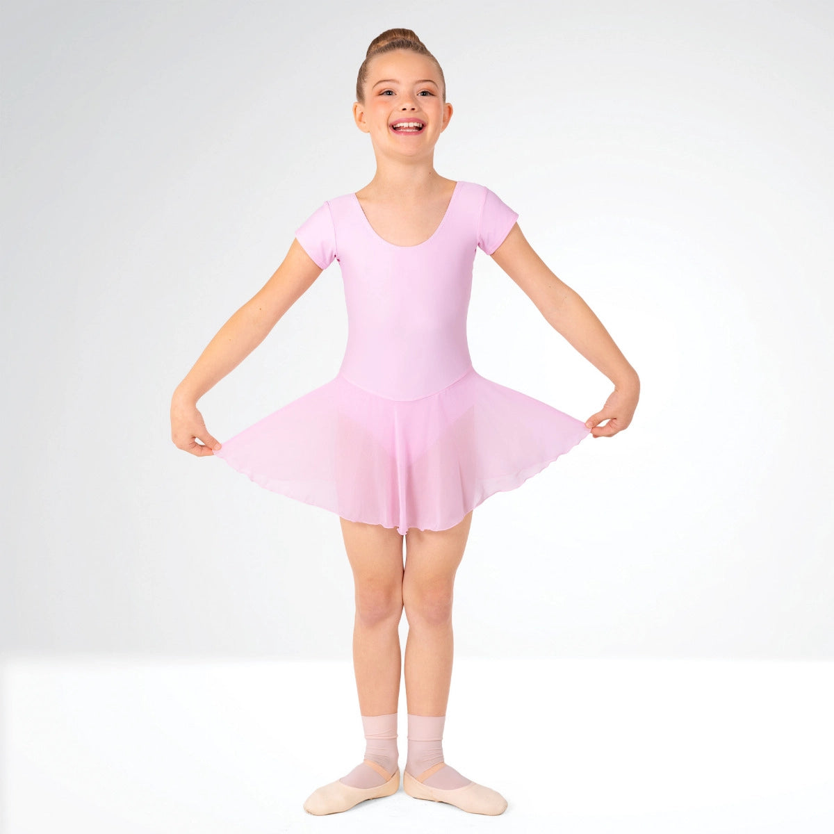 Young girl wearing a pink ballet dress on a white background