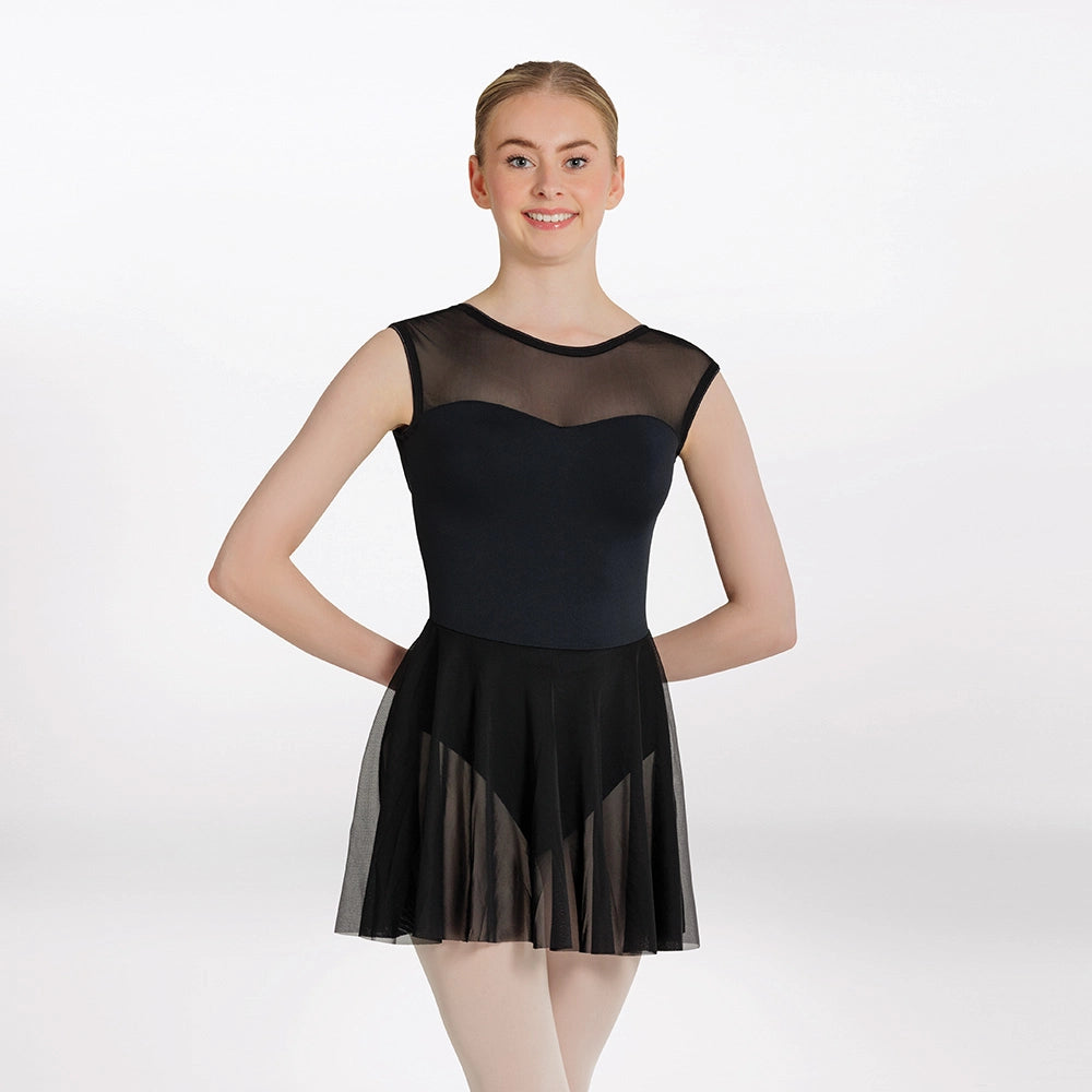 Woman wearing a black ballet dress with sheer overlay on a white background