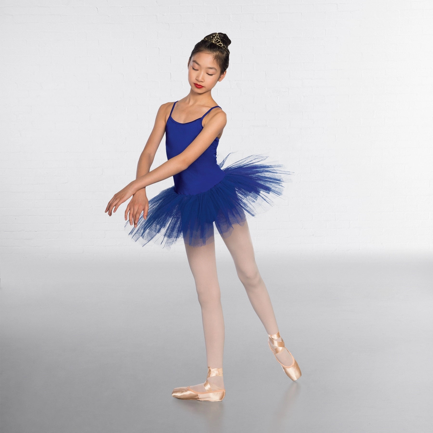 Ballerina in a blue tutu posing on a plain background