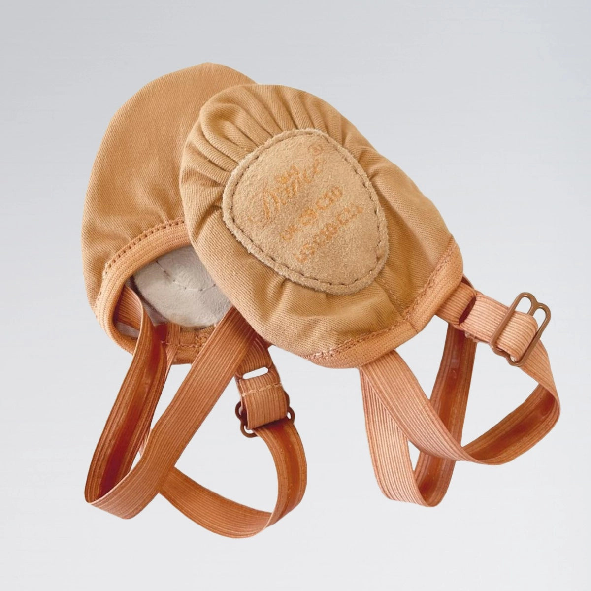Tan leather dog muzzle with straps on a light gray background