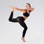 Person in black athletic wear performing a yoga pose on a light gray background