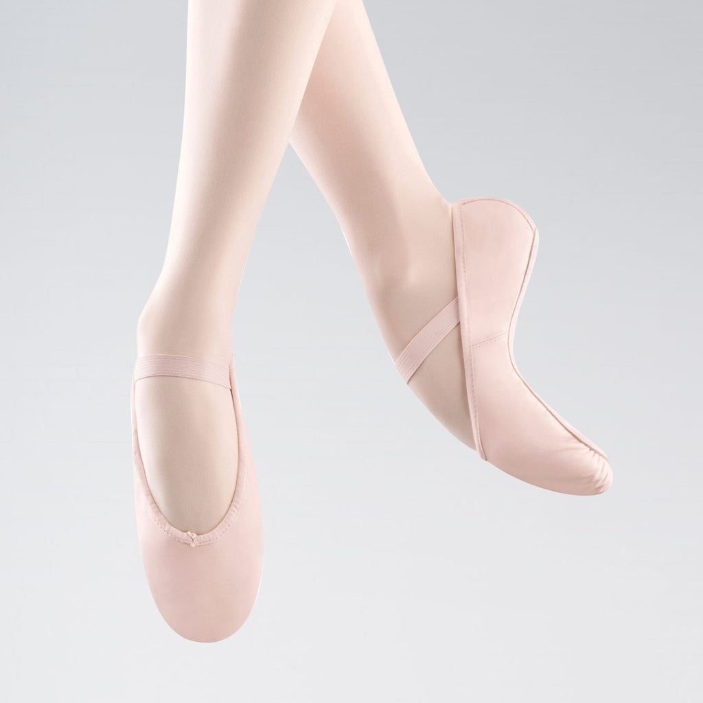 Pink ballet shoes worn by a person on a light gray background