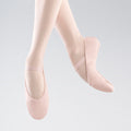 Pink ballet shoes worn by a person on a light gray background