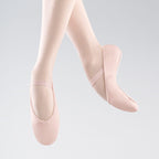 Pink ballet shoes worn by a person on a light gray background