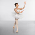 Ballerina in a white tutu posing on a light gray background